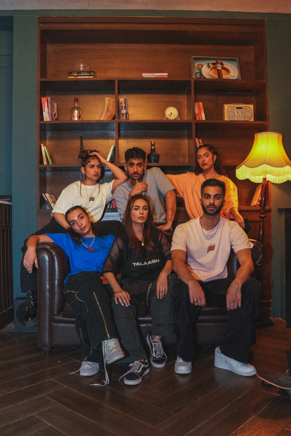 Six models wearing Talaash shirts in a warmly lit lounge
